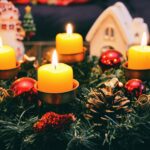 Cozy Christmas display featuring candles, ornaments, and festive wreath in warm candlelight.
